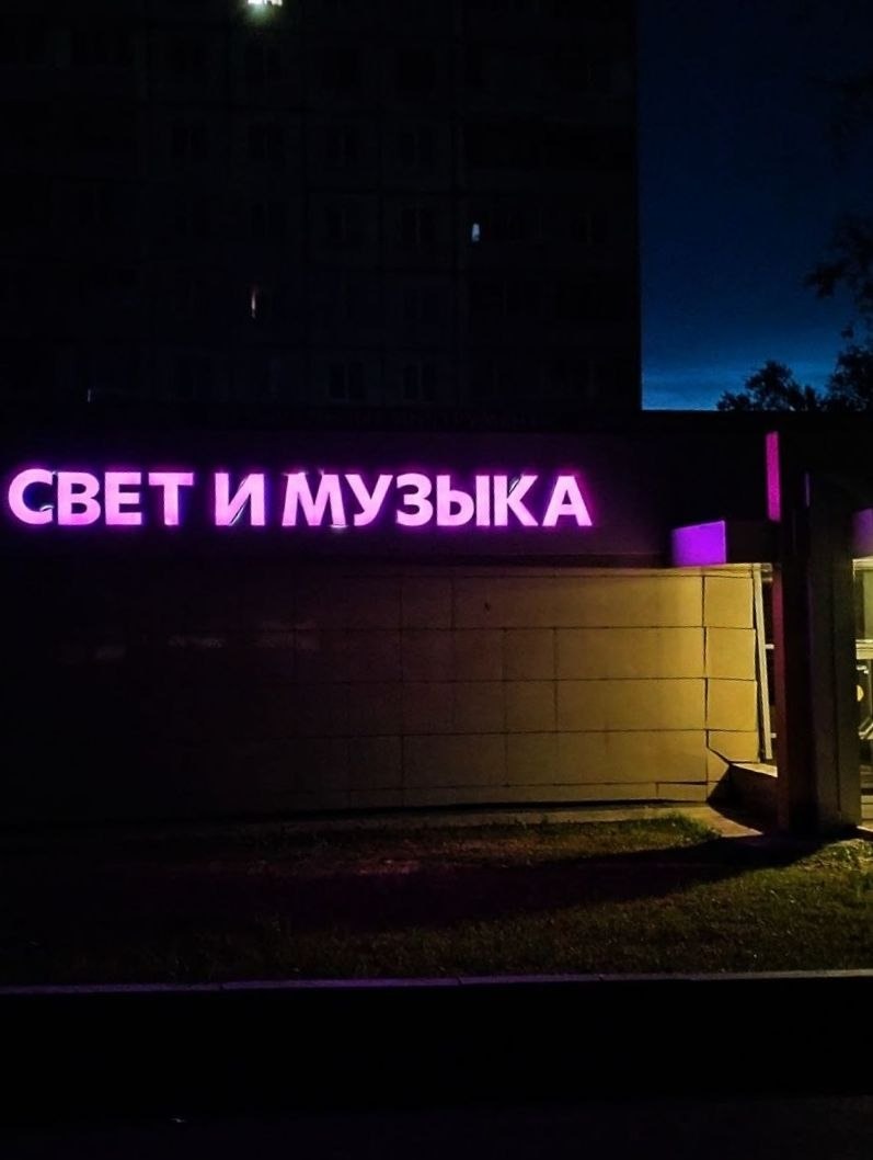 Светящаяся неоновая вывеска «Свет и музыка» в ночном городе.
